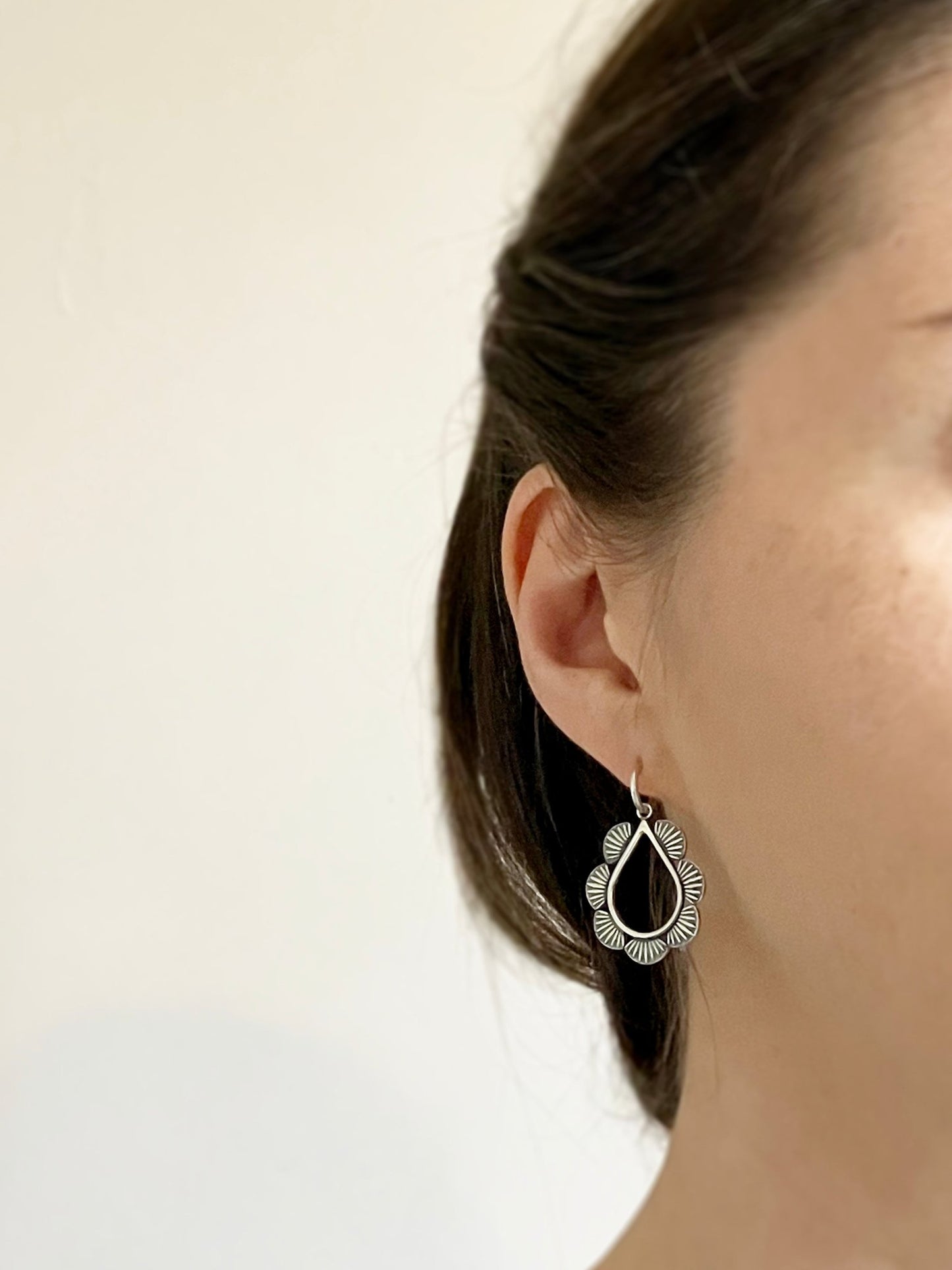 modelled photo to show huggie hoop hugs the earlobe and teardrop design is suspended from this - also shows how the oxidisation lets the detail stand out - styled with hair up, gives a bohemian, relaxed look