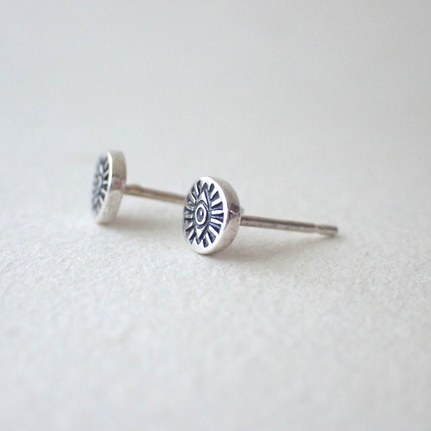 side view of handstamped eye studs to show depth of metal used (not thin) - the stamped oval has also been domed outward slightly to make the impression more visible
