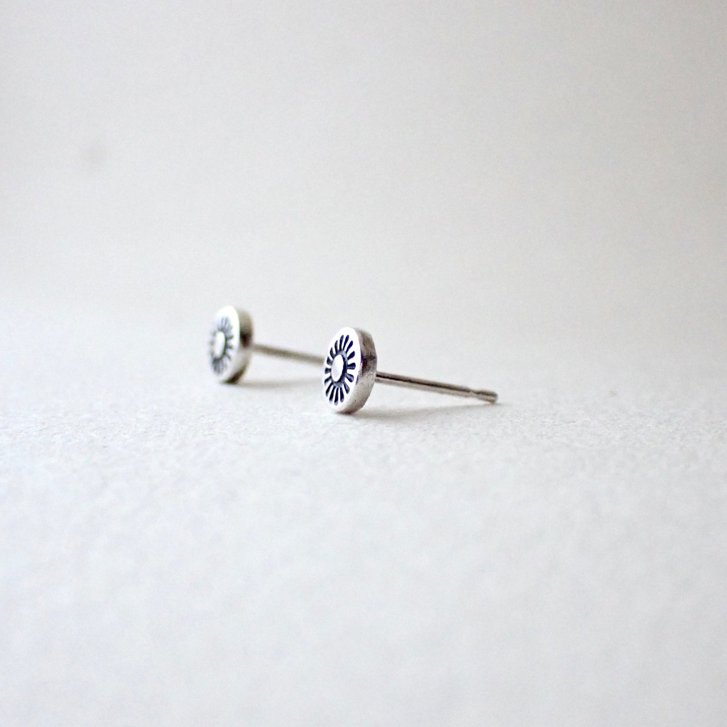 side view of hand-stamped sunshine earrings to show reasonably thick metal is used (this is slightly domed outwards to make the design more visible)