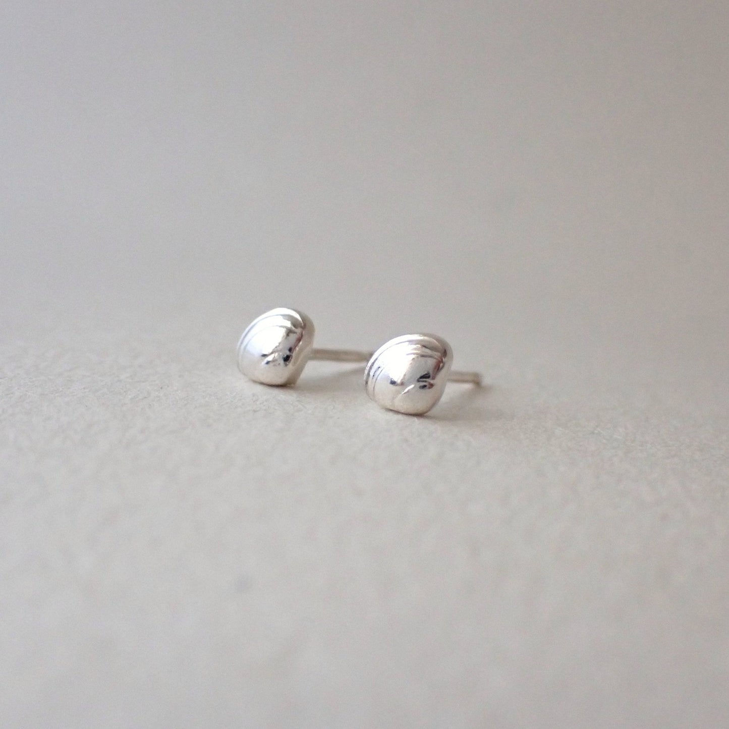 a pair of brighly polished and very shiny dinky clamshell stud earrings
