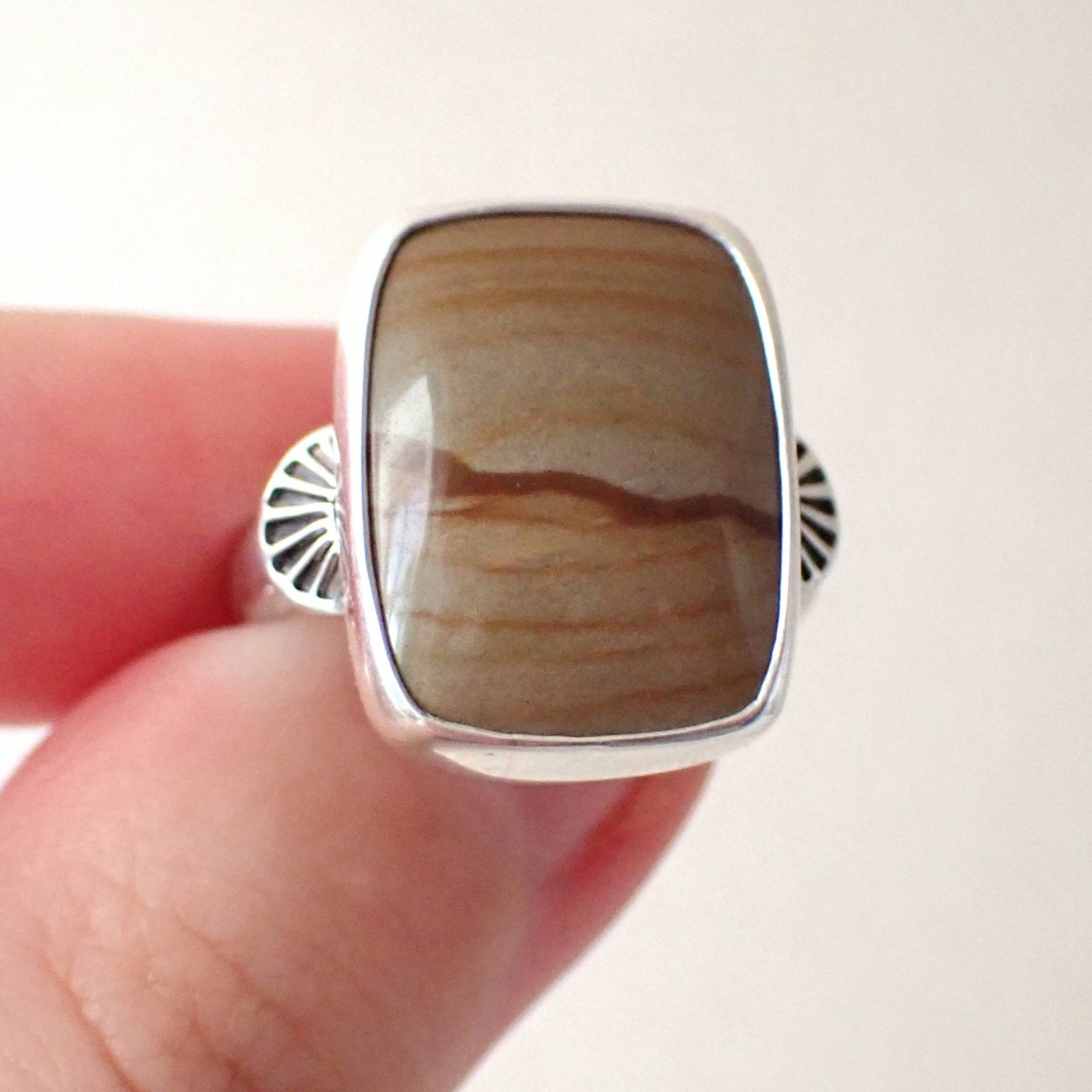 The ring held between finger and thumb which shows the corners of the set stone are rounded and smooth