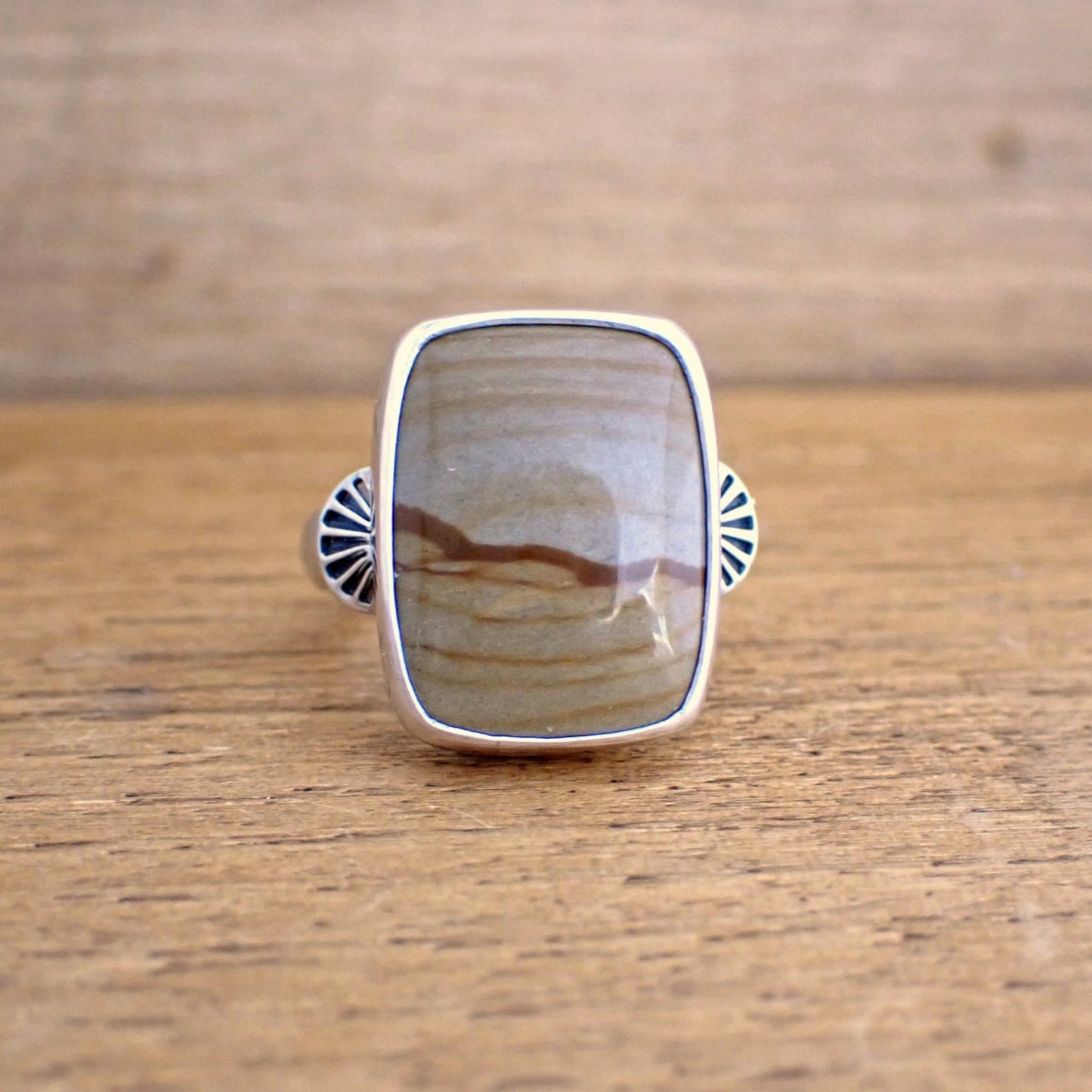 A face on view of the Roam ring which shows the two decorative stamped shoulders are set either side of the centre of the stone on the band of the ring