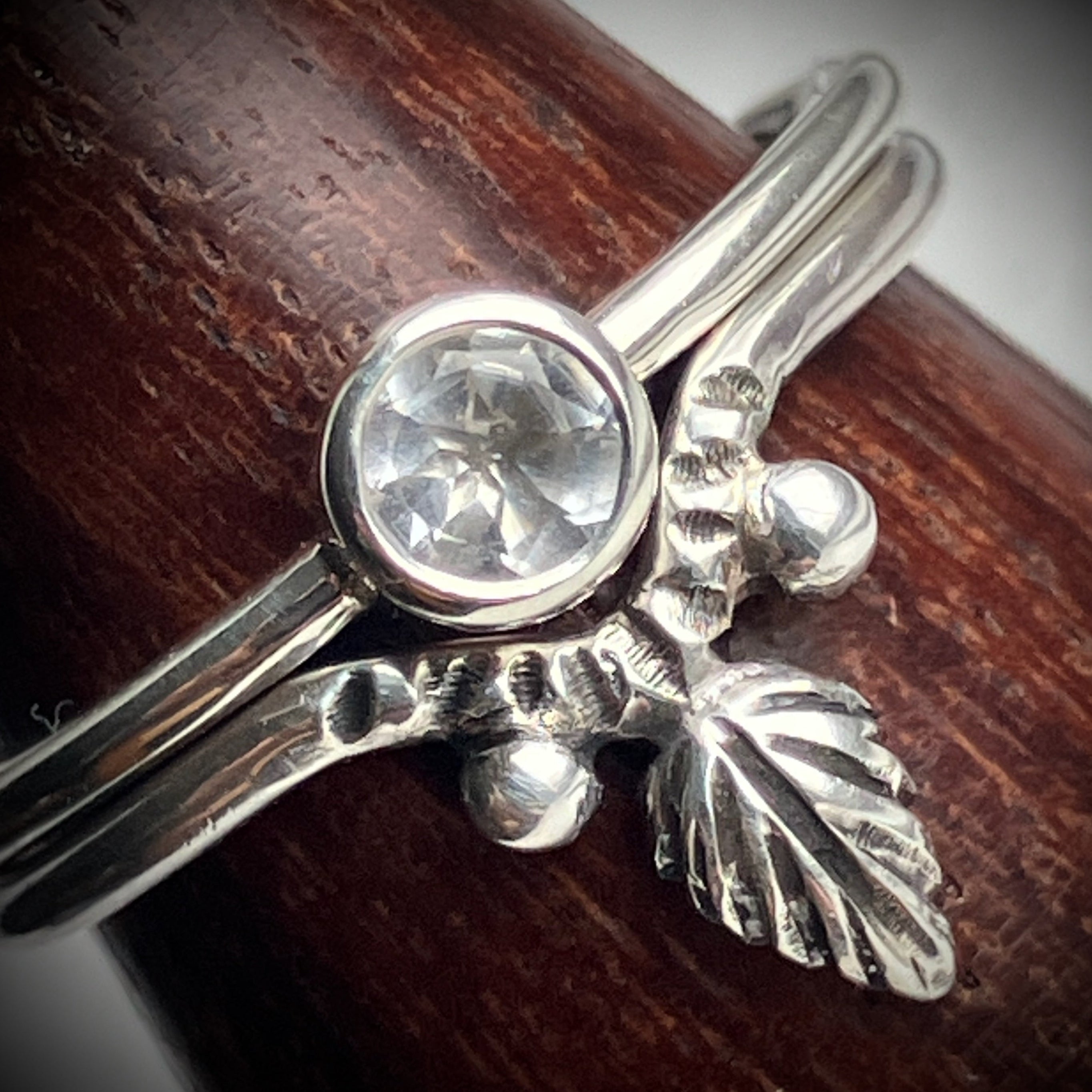 a set of two silver rings - one is a simple tube set crystal quartz and this sits on top of a wishbone with carved details, leaf carving coming from centre in a point and silver ball embellishments