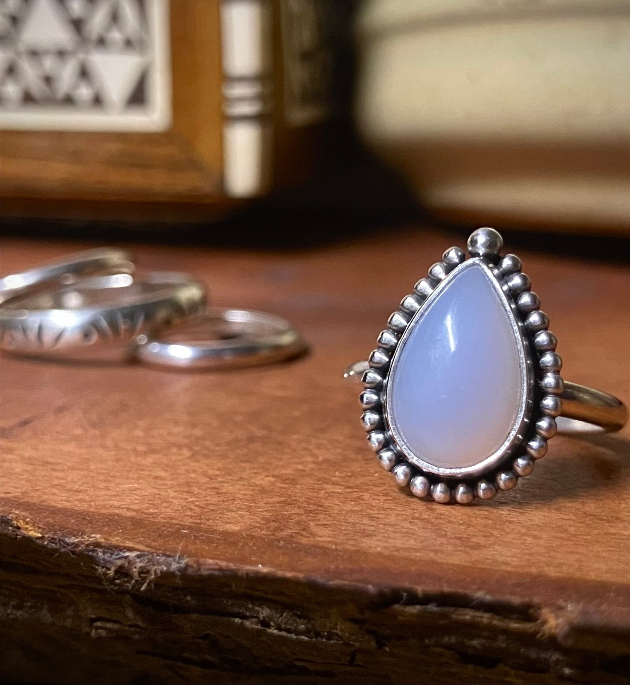 a handmade ring featuring a soft blue teardrop shaped gemstone, oxidised silver and beaded frame