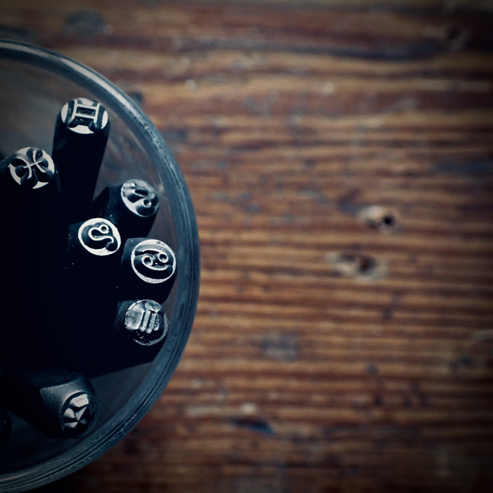 a bunch of steel stamps featuring horoscope symbols in a glass jar