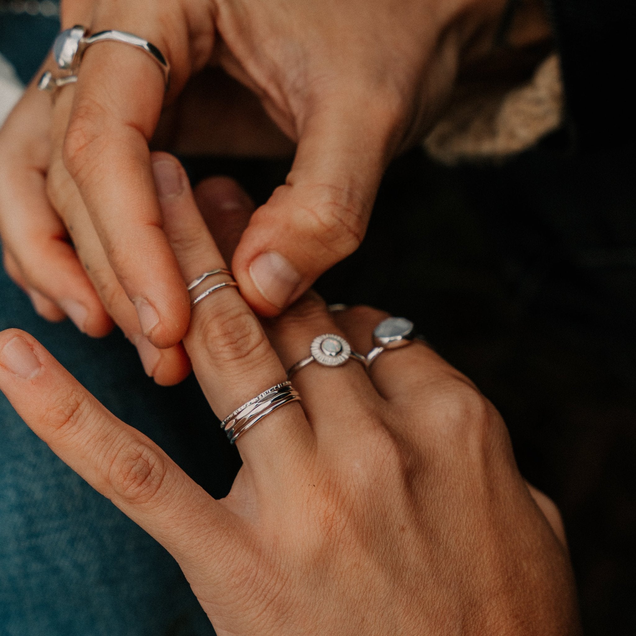 a person putting skinny silver rings on her hand