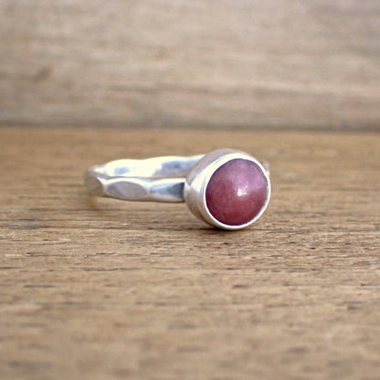 An angled side view of the Cherry Drop ring to show the facets hammered on to the band are large and elliptical in shape