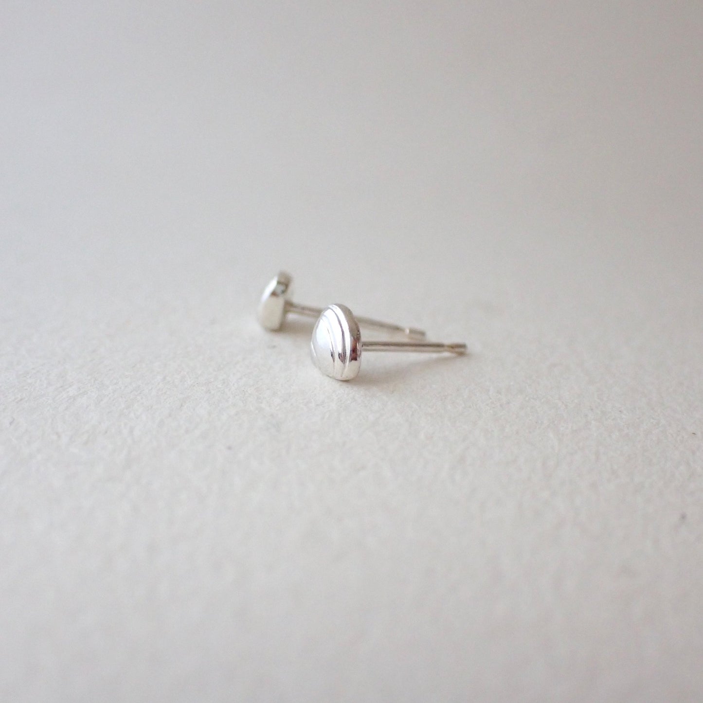 side view of handmade silver clamshell earrings to show depth of metal - 3D clamshell (domed with a flat back to sit against your earlobe) and with no sharp edges