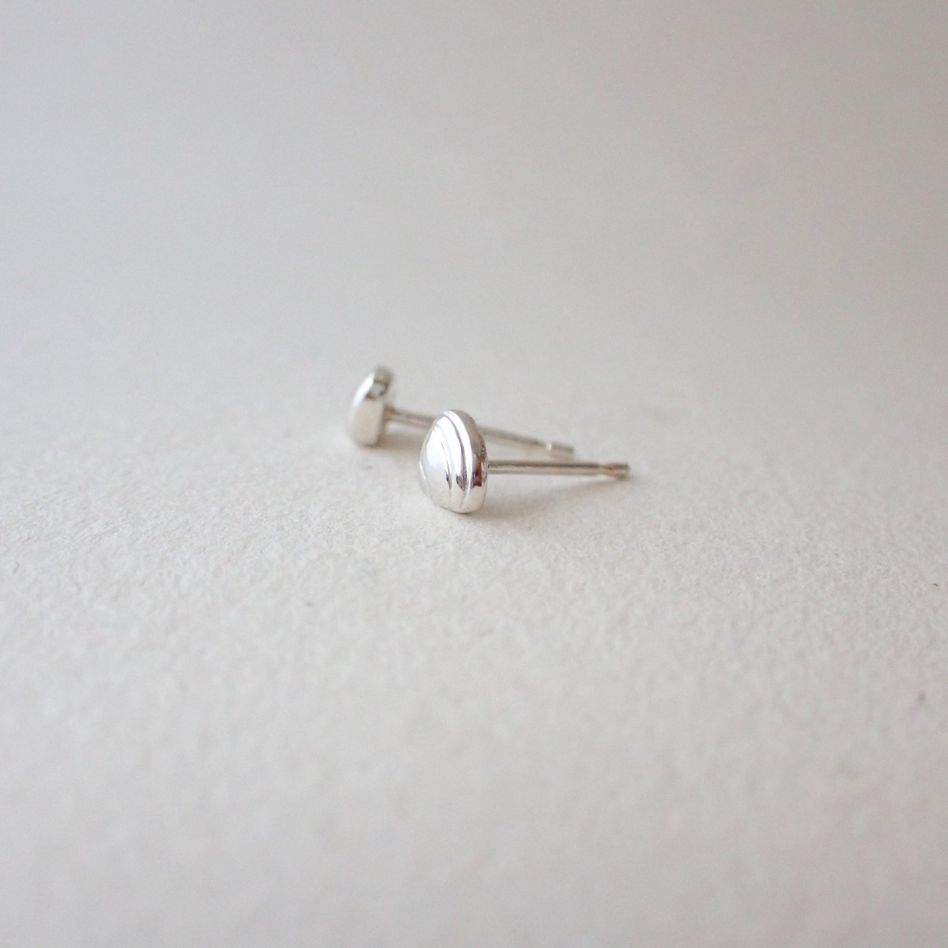 side view of handmade silver clamshell earrings to show depth of metal - 3D clamshell (domed with a flat back to sit against your earlobe) and with no sharp edges