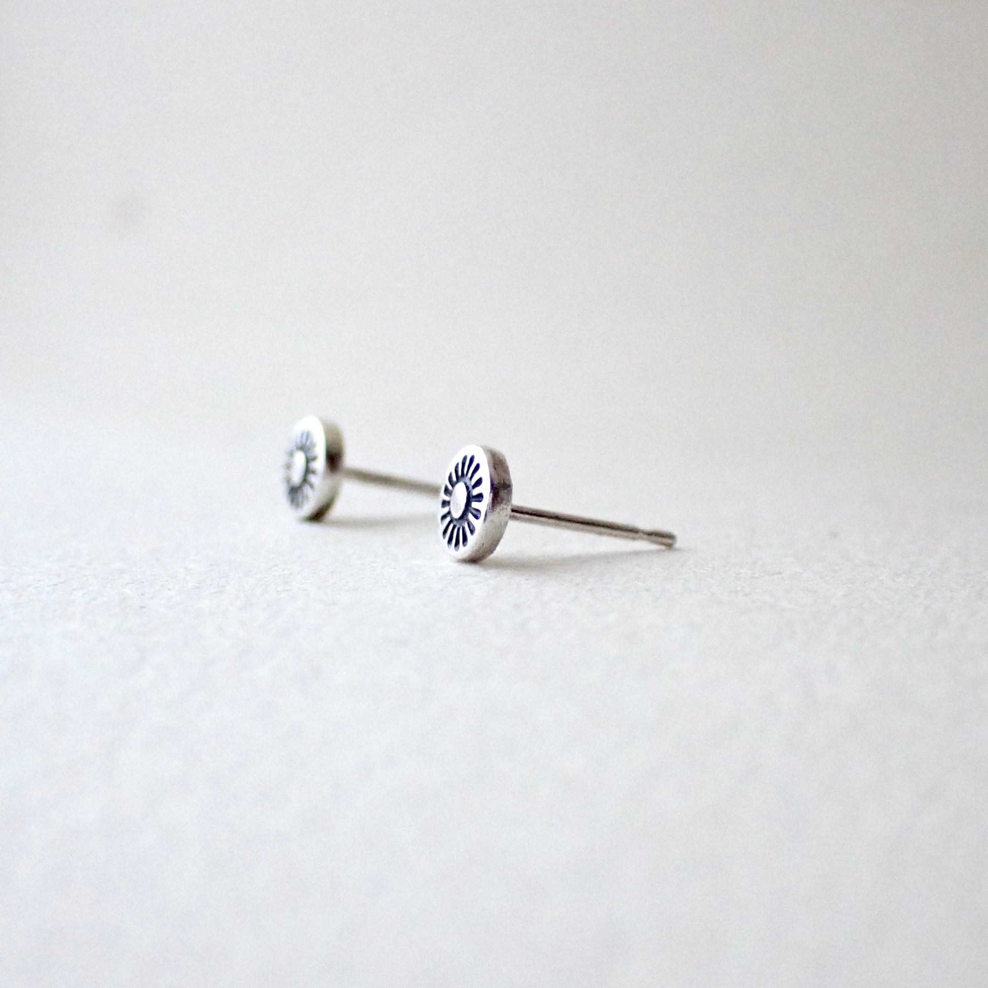 side view of hand-stamped sunshine earrings to show reasonably thick metal is used (this is slightly domed outwards to make the design more visible)