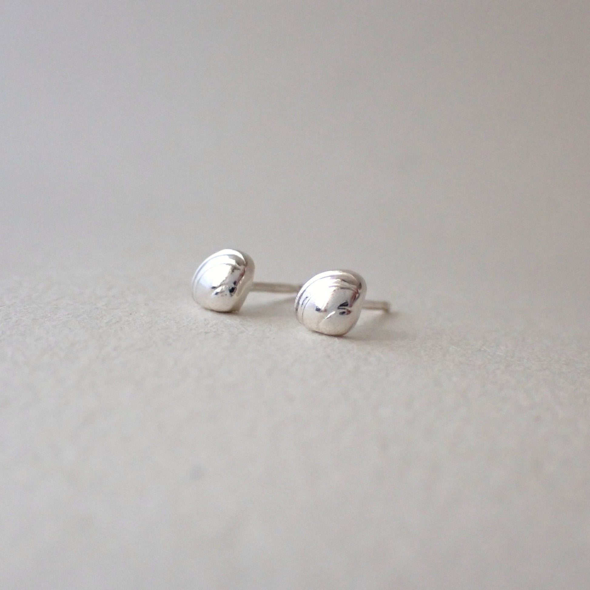 a pair of brighly polished and very shiny dinky clamshell stud earrings