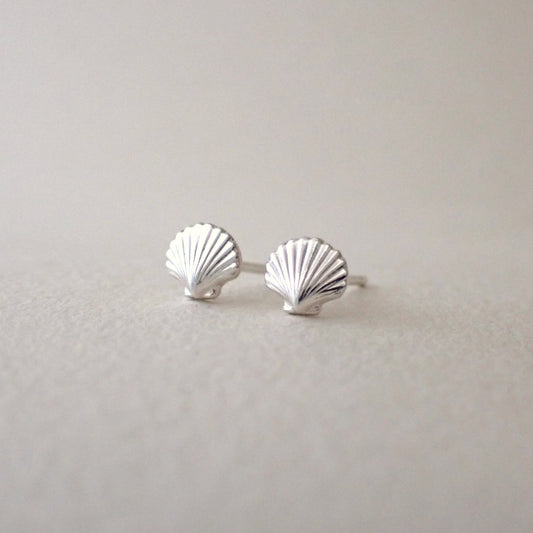 a pair of brightly polished silver scallop shell stud earrings side by side